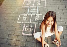 Beautiful Cheerful Little Girl Playing Hopscotch On Playground