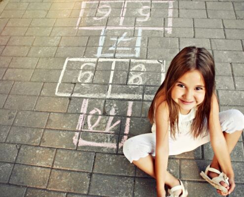 Beautiful Cheerful Little Girl Playing Hopscotch On Playground