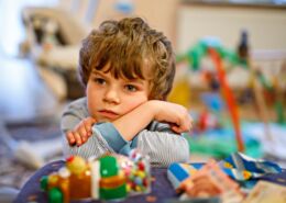 Portrait Of Little Kid Boy Sad On Birthday. Child With Lots Of Toy