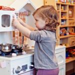 A Child Playing With A Fake Kitchen