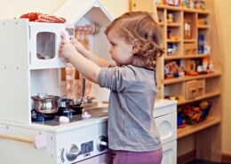 A Child Playing With A Fake Kitchen