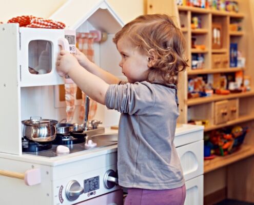 A Child Playing With A Fake Kitchen