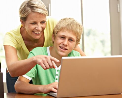 Mother Helping Her Teenage Son On The Laptop